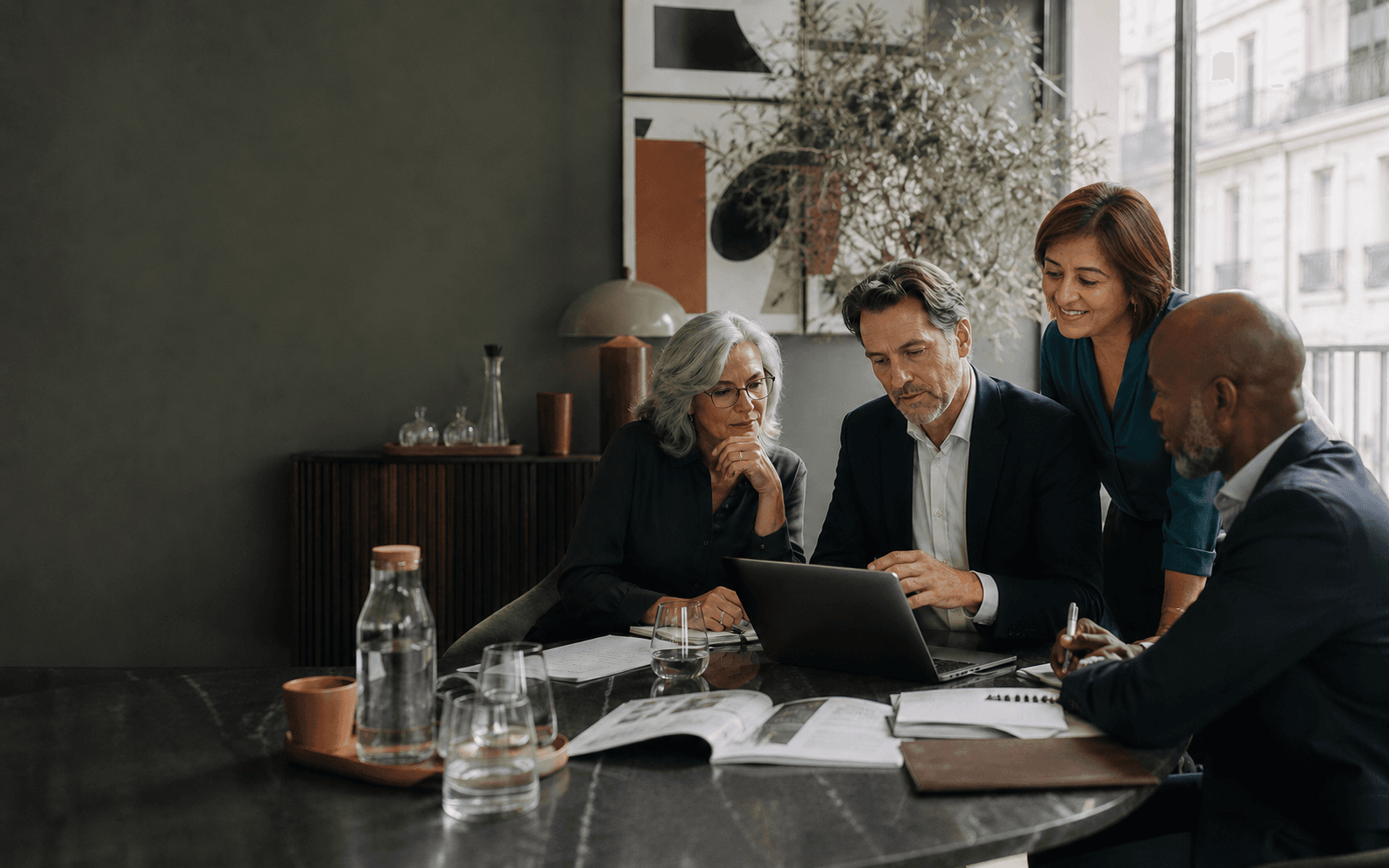 Compliance team reviewing documents and a laptop around a meeting table